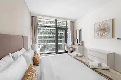 a white bedroom with a large bed and a window at VayK - Great 1BR with Beach Access in Dubai