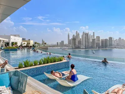 a group of people sitting in hammocks in a pool at a hotel at VayK - Great 1BR with Beach Access in Dubai