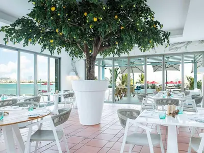 a restaurant with a tree and white tables and chairs at Upscale 1BR with Beach Access on Palm Jumeirah in Dubai