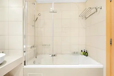 a bathroom with a tub and a glass shower at VayK - Beachfront 1BR on Palm Jumeirah with Sea View in Dubai