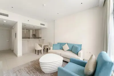 a living room with a blue couch and a table at VayK - Modern 1BR on Palm Jumeirah in Dubai