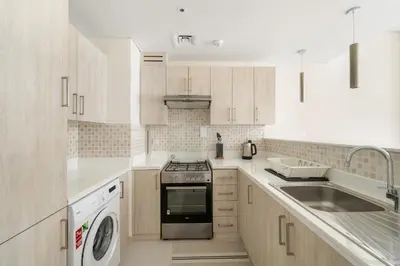 a white kitchen with a stove top oven next to a sink at VayK - Modern 1BR on Palm Jumeirah in Dubai