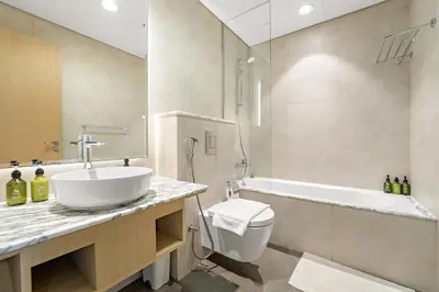 a bathroom with a sink and a tub and a toilet at VayK - Spacious 2BR Inside Hotel in Dubai