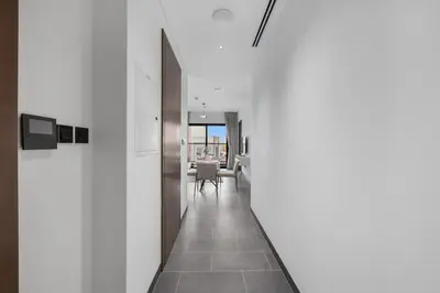 a hallway with white walls and a table and chairs at Modern 1BR Apartment with Balcony in Sobha Hartland in Dubai