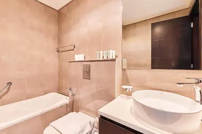 a bathroom with a sink and a tub and a toilet at Home Away 2BR in Dubai