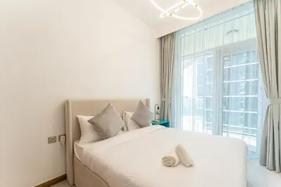 a bedroom with a white bed with a large window at HAVN - 2 bedroom in Urban Oasis, Dubai Canal View in Dubai