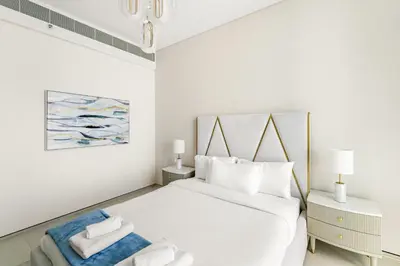 a white bedroom with a large bed with white pillows at VayK - Luxurious 2BR Beachfront Retreat with Ocean View in Dubai