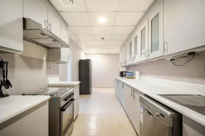 a kitchen with white cabinets and a black refrigerator at Luxury Beachfront 4BR with Sea & Marina Views in Dubai