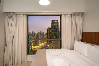 a bedroom with a large window with a city view at Luxury Beachfront 4BR with Sea & Marina Views in Dubai