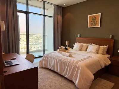 a bedroom with a bed and a desk with a laptop at Spacious 1BR- Sepcoo III Residence Al Furjan-1009 in Dubai