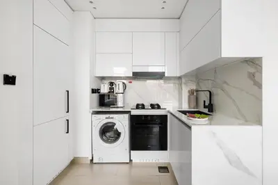 a kitchen with white cabinets and a washer and dryer at New! Cozy 1BR in Binghatti House Pool and Gym in JVC in Dubai