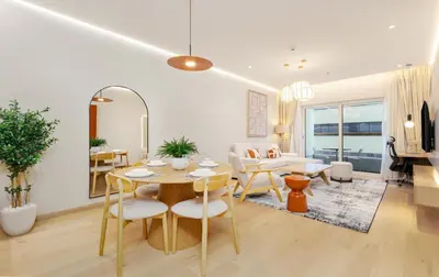 a dining room and living room with a table and chairs at Vacay Lettings - Elite Residence - 1 BR - Partial Sea View in Dubai