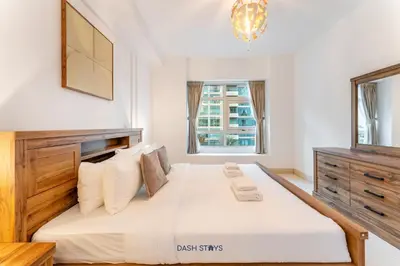 a white bedroom with a large bed and a window at Lux 2BR in Dubai Marina Walk to Beach & Metro in Dubai
