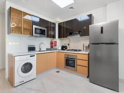a kitchen with a refrigerator and a washing machine at Blissful Retreat 1BR with 1GR Study Sleeps 4 in Gemz 05 in Dubai