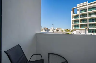 a balcony with two chairs and a building at ALiving Brand New & Modern Studio I Binghatti Galaxy, JVC- G01 in Dubai
