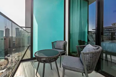 two chairs and a table on the balcony of a building at Stylish 1BR Studio Unit Balcony & Pool in Dubai