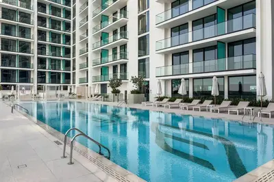 a large swimming pool with chairs and a building at Stylish 1BR Studio Unit Balcony & Pool in Dubai