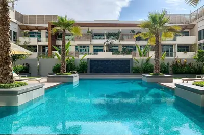 a swimming pool in front of a building with palm trees at Frank Porter - Oxford Boulevard in Dubai