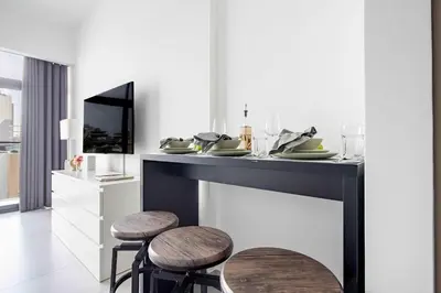 a dining table with stools and a television in a room at Frank Porter - Oxford Boulevard in Dubai