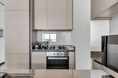 a kitchen with white cabinets and a stove top oven at GuestReady - 1BR l Burj Khalifa & Canal Views in Dubai
