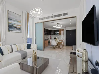 a living room with a white couch and a tv at Velvet Luxe Modern - 1BR w Private Pool in Gemz-15 in Dubai