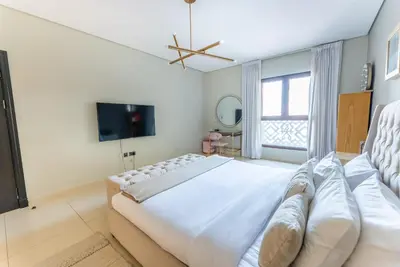 a white bedroom with a large bed and a tv at Luxury Palm Jumeirah Apartment with Sea Views Balqis Residence in Dubai
