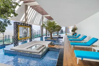 a pool with blue lounge chairs and a swimming pool at Famous Sky Pool - Paramount Midtown - Dubai Skyline Views in Dubai