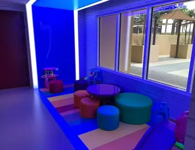 a room with colorful chairs and a table and windows at Glamorous Luxe Studio in Ghalia-JVC-12 in Dubai