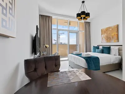 a hotel room with a bed and a table and a chair at Glamorous Luxe Studio in Ghalia-JVC-12 in Dubai