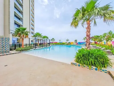 a swimming pool with palm trees and a building at Sophisticated 2BDR Living In Aykon City Business B in Dubai