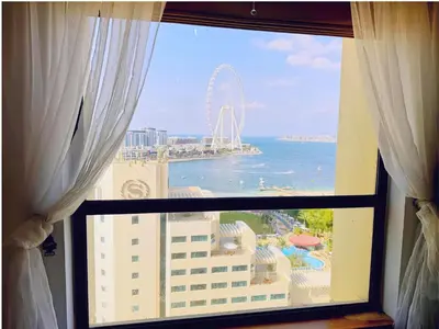 a window with a view of the ocean and a ferris wheel at JBR l Full Sea View l 4BR l 3min to Beach l 7-12PAX in Dubai