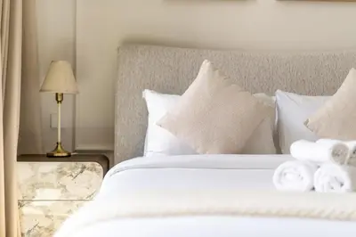 a bedroom with a bed with white sheets and pillows at New! Elegant 1BR Flat in Creek Harbour with Pool&Gym in Dubai