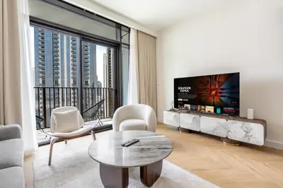 a living room with a tv and a table and chairs at New! Elegant 1BR Flat in Creek Harbour with Pool&Gym in Dubai