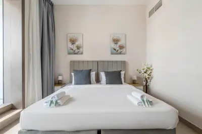 a bedroom with a large white bed with two pillows at New! Serene 2BR with Balcony & Pool in Sparkle Tower in Dubai