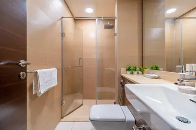 a bathroom with a shower and a toilet and a sink at New! Serene 2BR with Balcony & Pool in Sparkle Tower in Dubai