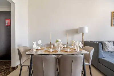 a dining room table with chairs and a blue couch at New! Serene 2BR with Balcony & Pool in Sparkle Tower in Dubai