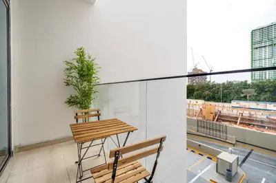 a balcony with a table and chairs and a plant at New! Stylish 1BR with Balcony and Pool Elysee III JVC in Dubai