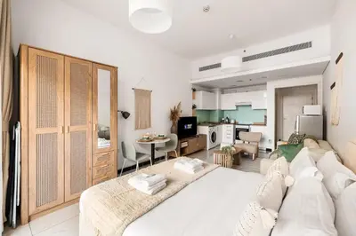 a living room with a white couch and a kitchen at New! Serene Studio with Balcony and Pool Crystal Res in Dubai
