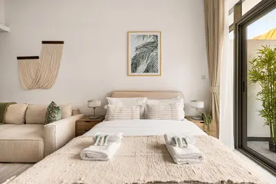 a white bedroom with a bed and a couch at New! Serene Studio with Balcony and Pool Crystal Res in Dubai