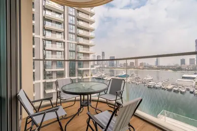a balcony with a table and chairs and a view of the water at New! Stunning 2BR wBalcony and Pool Marina Vista in Dubai