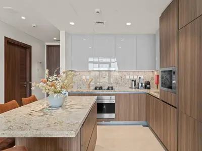 a kitchen with a marble counter top and wooden cabinets at Urban Compact 2BKH Sleeps 4 Full Burj Khalifa View in Dubai