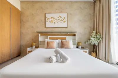 a bedroom with a large white bed with two pillows at New! Spacious 2BR with Burj Views in Marquise Square in Dubai