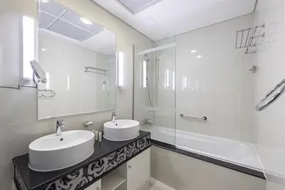 a white bathroom with two sinks and a shower at Damac Maison Mall Street! Upgraded 3 Bedroom with Burj and DIFC views! Nearest to Dubai Mall in Dubai