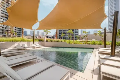 an outdoor pool with chairs and an umbrella and a pool at Luxury 3 Bedroom Apartment, 8 mins from Dubai Mall, Sleeps 6 people in Dubai
