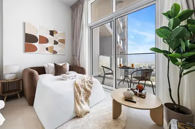 a living room with a white couch and a large window at Cozy Studio with 31st Floor Miracle Garden View in Dubai