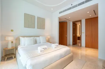 a bedroom with a large white bed with two towels on it at PVH - Ellington Beach House - Luxurious 1BR with Private Beach Access in Dubai