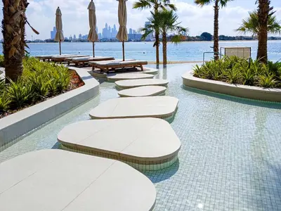 a row of tables and umbrellas in a swimming pool at PVH - Ellington Beach House - Luxurious 1BR with Private Beach Access in Dubai