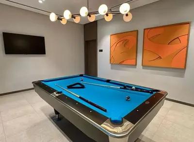 a pool table in a room with a tv and paintings at Grande Essence Elegant 1BR Sleeps 4 in Downtown in Dubai