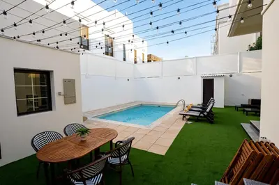 a patio with a table and chairs and a swimming pool at Iconic Villa in Dubai