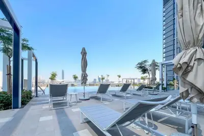 a patio with lounge chairs and a swimming pool at Creek Harbour Gem Stylish 2BR with Stunning Views-17 in Dubai